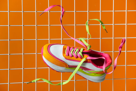 Stylish presentation of trendy sneaker on orange backgroundの写真素材