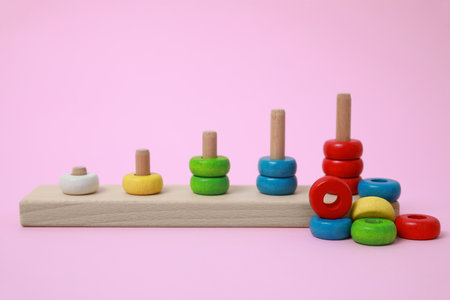 Stacking and counting game wooden pieces on pink background. Educational toy for motor skills developmentの写真素材