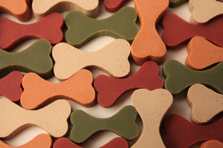 Many bone shaped vitamins for pets on beige background, closeup