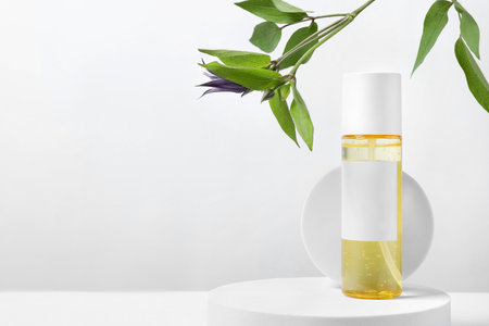 Bottle of cosmetic product and leaves on white wooden table. Space for textの写真素材