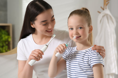 Mother and her daughter brushing teeth together in bathroomの写真素材