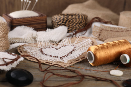 Pieces of burlap fabric with different stitches and sewing tools on wooden tableの写真素材