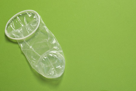 Unrolled female condom on green background, above view and space for text. Safe sexの写真素材