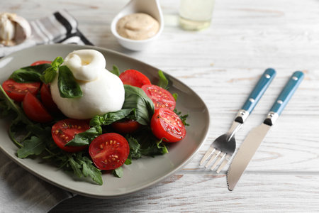 Delicious burrata cheese served with tomatoes and basil on white wooden table, closeupの写真素材