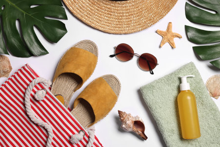 Flat lay composition with bag, green leaves and other beach accessories on white backgroundの写真素材