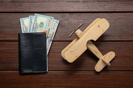 Dollars, passport and model of plane on wooden table, flat lay. Business tripの写真素材