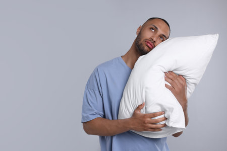 Sleepy man with pillow on light grey background, space for text. Insomnia problemの写真素材