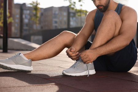 Man tying shoelaces before running outdoors on sunny day, closeupの写真素材