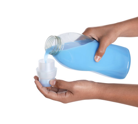 Woman pouring fabric softener from bottle into cap on white background, closeupの写真素材