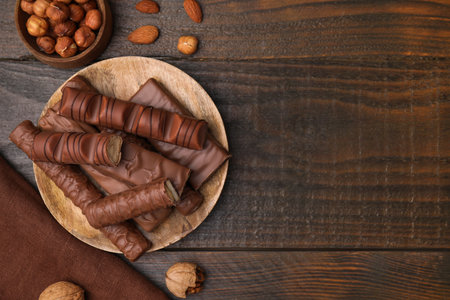 Different tasty chocolate bars and hazelnuts on wooden table, flat lay. Space for textの写真素材