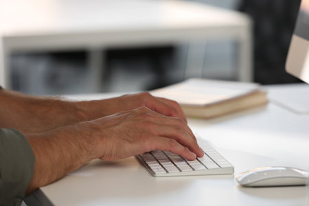 Man using modern computer keyboard at white desk in office, closeupの写真素材