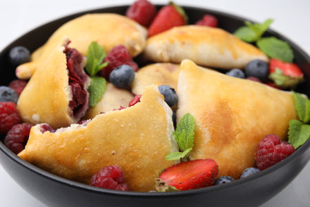 Bowl with delicious samosas, berries and mint leaves on table, closeupの写真素材