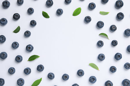 Tasty fresh blueberries with green leaves on white background, flat lay. Space for text