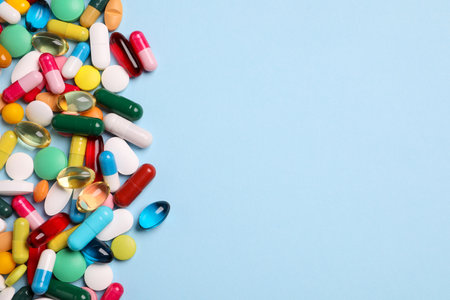 Many different pills on light blue background, flat lay. Space for textの写真素材