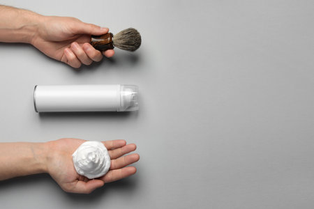 Man with shaving foam, brush and bottle on light gray background, top view. Space for textの写真素材