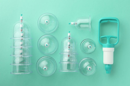 Plastic cups and hand pump on turquoise background, flat lay. Cupping therapyの写真素材