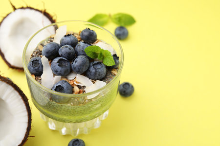 Tasty chia matcha pudding with coconut and blueberries on yellow background, space for text. Healthy breakfastの写真素材