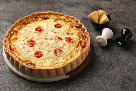 Delicious homemade cheese quiche and spices on gray table
