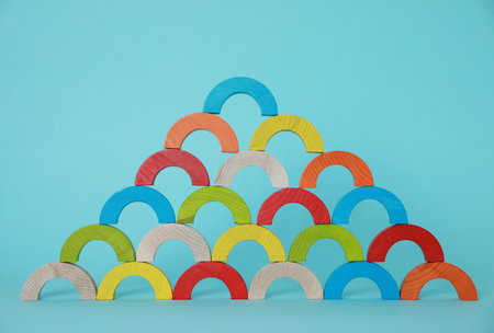 Colorful wooden pieces of playing set on light blue background. Educational toy for motor skills...