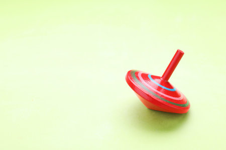 One bright spinning top on light green background, space for text. Toy whirligigの写真素材