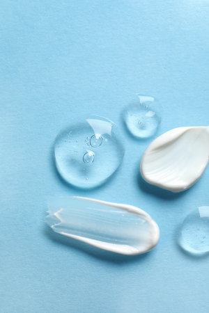 Samples of transparent gel and white cream on light blue background, flat layの写真素材