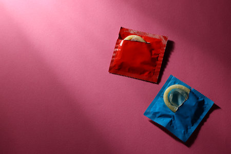 Condoms in torn packages on pink background, top view with space for text. Safe sexの写真素材