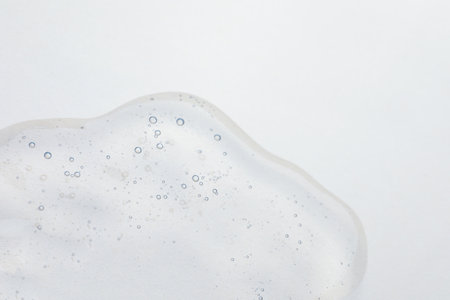 Sample of cosmetic oil on beige background, closeup