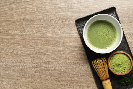 Cup of fresh matcha tea, bamboo whiskey and green powder on wooden table, top view. Space for textの写真素材