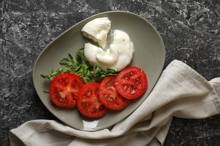 Delicious burrata cheese with tomatoes and arugula on gray table, flat layの写真素材