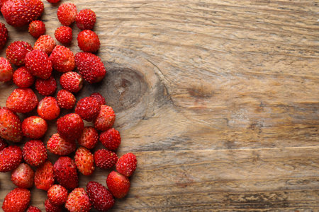 Many fresh wild strawberries on wooden table, flat lay. Space for textの写真素材
