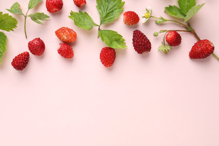 Many fresh wild strawberries and leaves on beige background, flat lay. Space for text