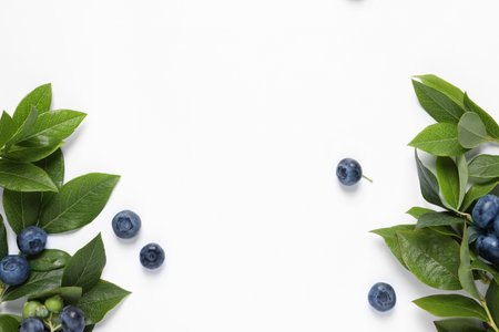 Tasty fresh blueberries with green leaves on white background, flat lay. Space for textの写真素材
