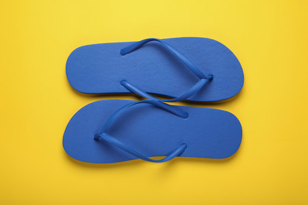 Stylish blue flip flops on yellow background, top viewの写真素材