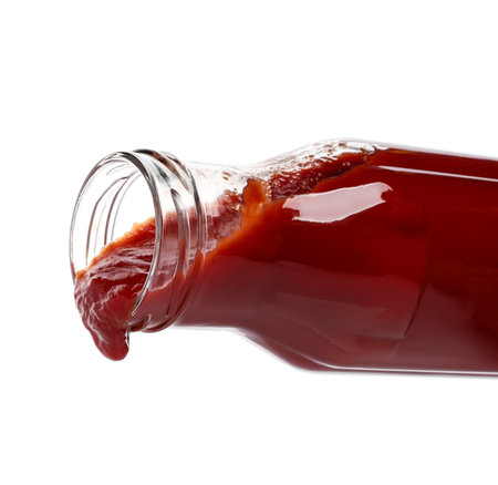 Pouring tasty red ketchup from glass bottle isolated on whiteの写真素材