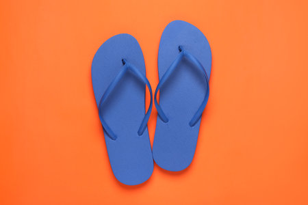 Stylish blue flip flops on orange background, top viewの写真素材