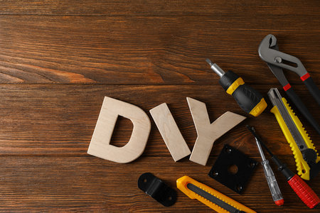 Abbreviation DIY made of letters and different tools on wooden table, flat lay. Space for textの写真素材