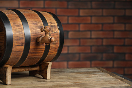 Wooden barrel with tap on table near brick wall, space for textの写真素材
