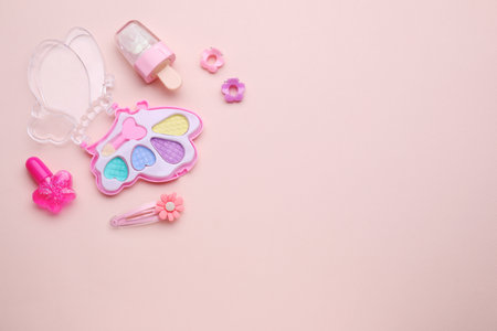 Eye shadow palette and other decorative cosmetics for kids on pink background, flat lay. Space for textの写真素材