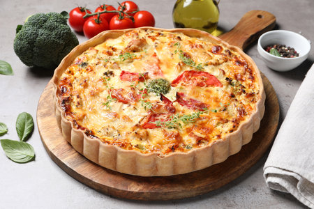 Tasty cheese quiche and ingredients on light gray tableの写真素材