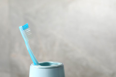 Plastic toothbrush in holder on light gray background, closeup. Space for textの写真素材