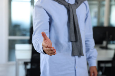 Man welcoming and offering handshake indoors, closeupの写真素材