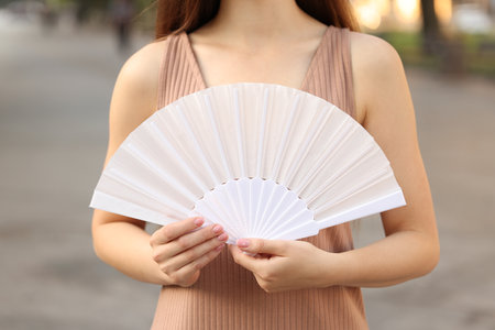 Woman with white hand fan outdoors, closeupの写真素材