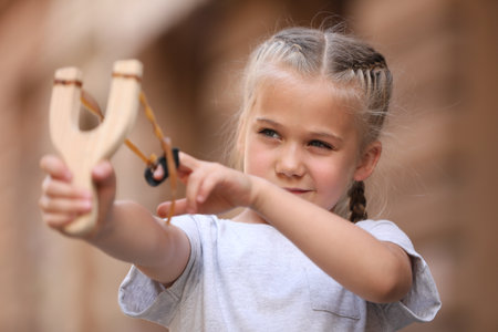 Little girl playing with slingshot on city street