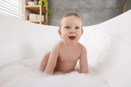 Cute little baby bathing in tub at home