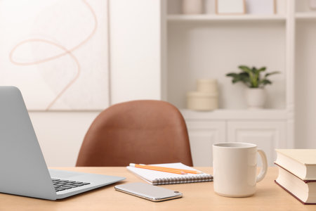 Home office. Laptop, cup, smartphone and stationery on wooden desk indoors. Space for textの写真素材