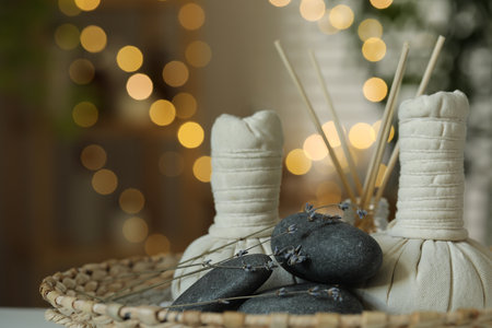 Spa composition. Herbal bags, stones, reed diffuser and dry lavender flowers in wicker tray indoors, bokeh effectの写真素材