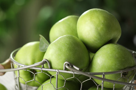 Metal basket with ripe green apples on blurred background, closeupの写真素材