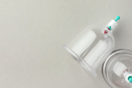 Plastic cups on light gray background, flat lay with space for text. Cupping therapy