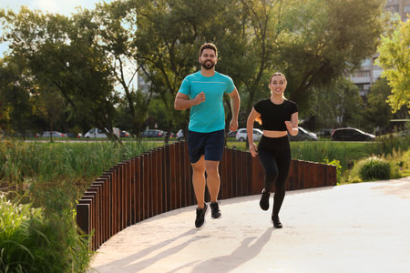 Healthy lifestyle. Happy couple running outdoors on sunny dayの写真素材