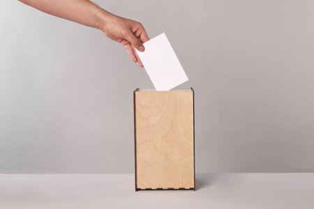 Man putting his vote into ballot box on light gray background, closeupの写真素材